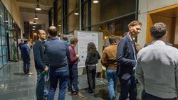 Menschen im Gespräch vor Posterausstellung.