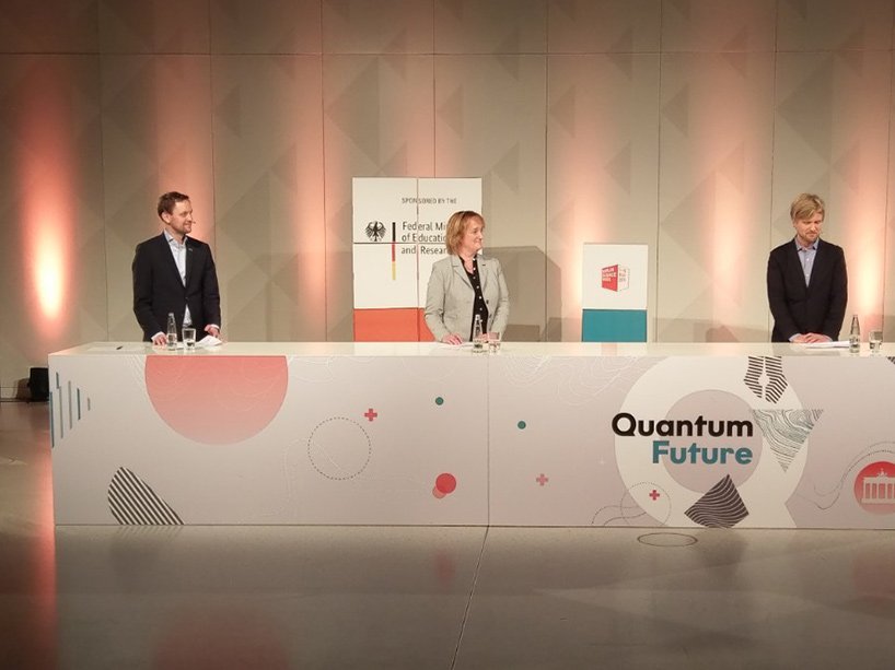 Die Mitglieder der Jury an einem Tisch, daneben ein Bildschirm mit den Finalist*innen sowie die Moderatorin