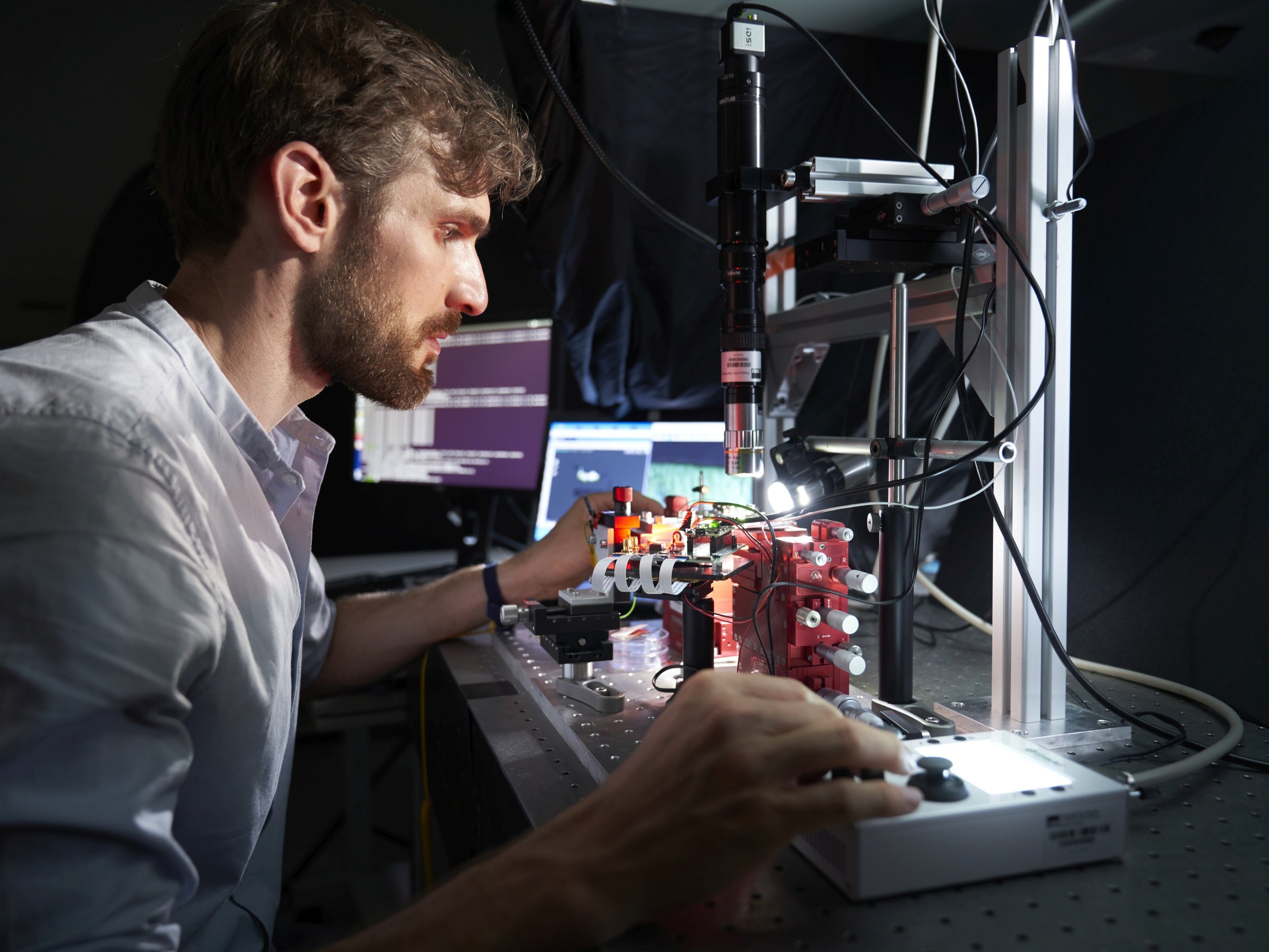 Forschender vor Mikroskopaufbau