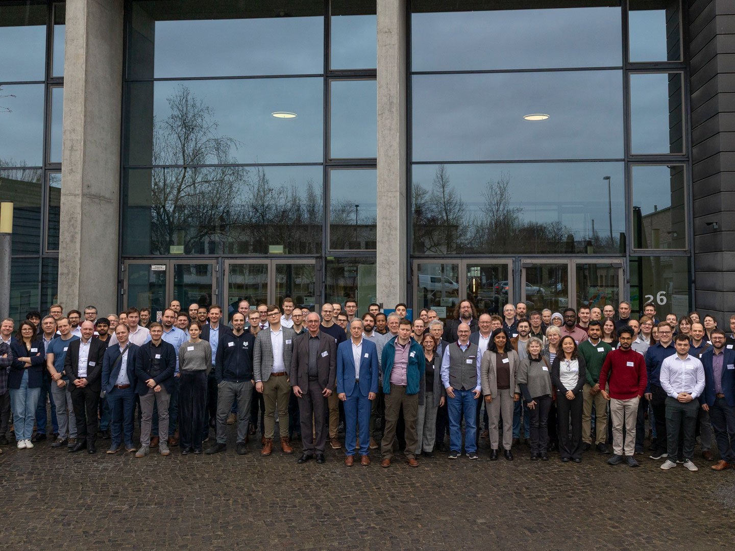 Etwa 100 Personen posieren für ein Foto vor Gebäude