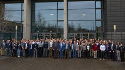 Etwa 100 Personen posieren für ein Foto vor Gebäude